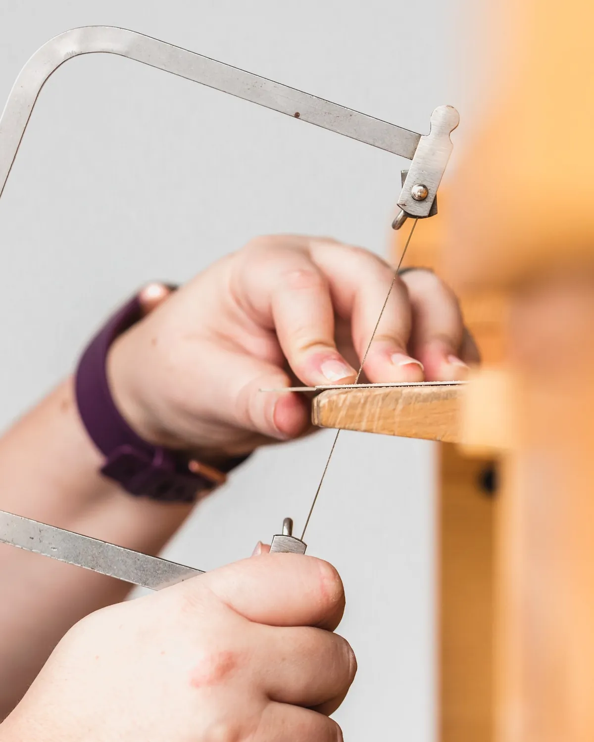 Hands piercing sheet metal with a jeweller's saw