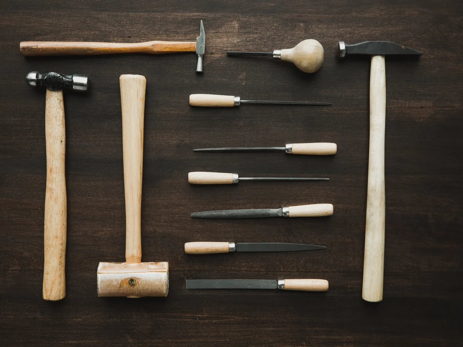 Jeweller's hammers and files laid out on dark wood