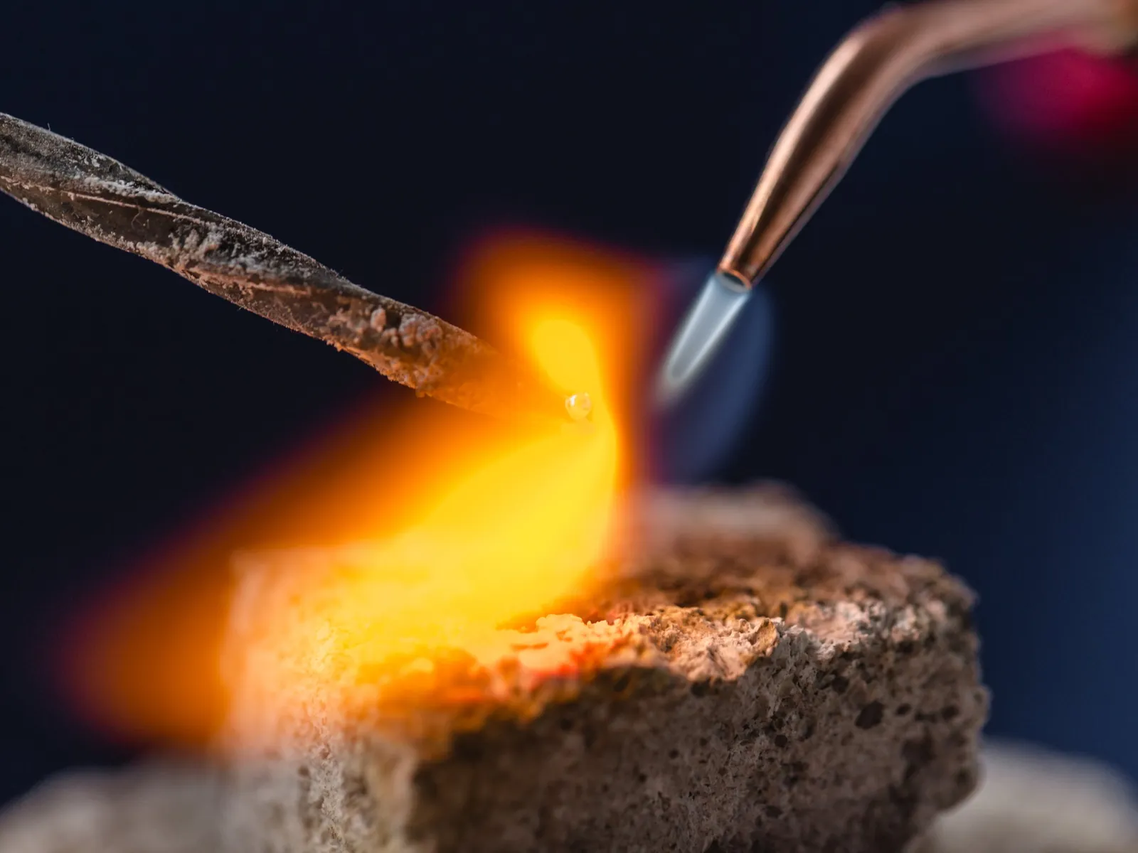 A torch flame heating a gold ring on a soldering block