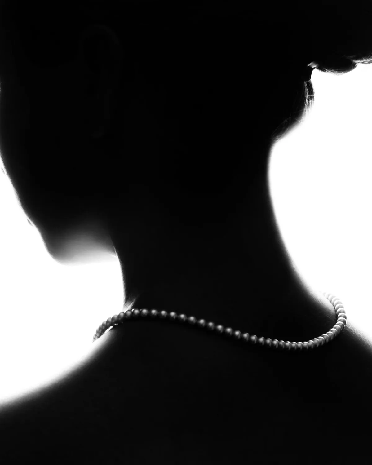 Silhouette of a woman wearing a pearl necklace